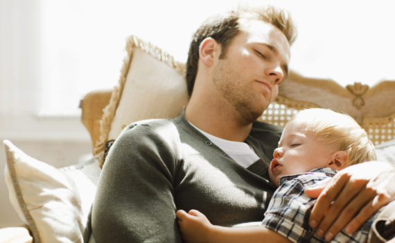 Father napping with son on sofa